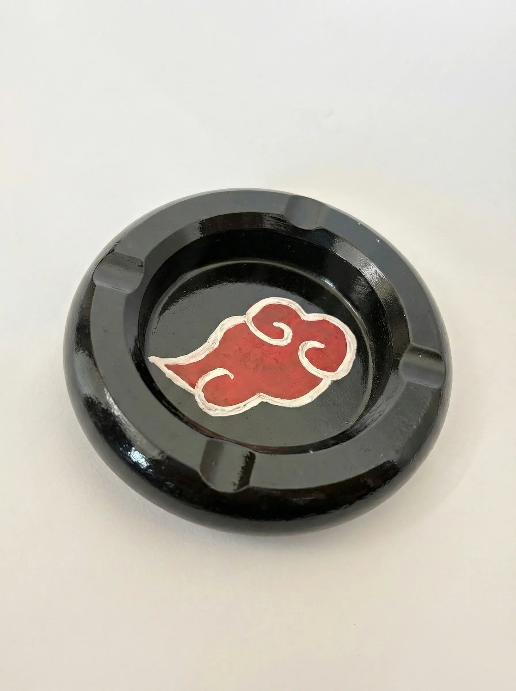 Black ashtray with a red akatsuki cloud symbol on a white background