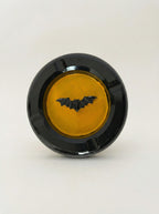 Black concrete bat-man ashtray with a yellow center and bat design on a white background
