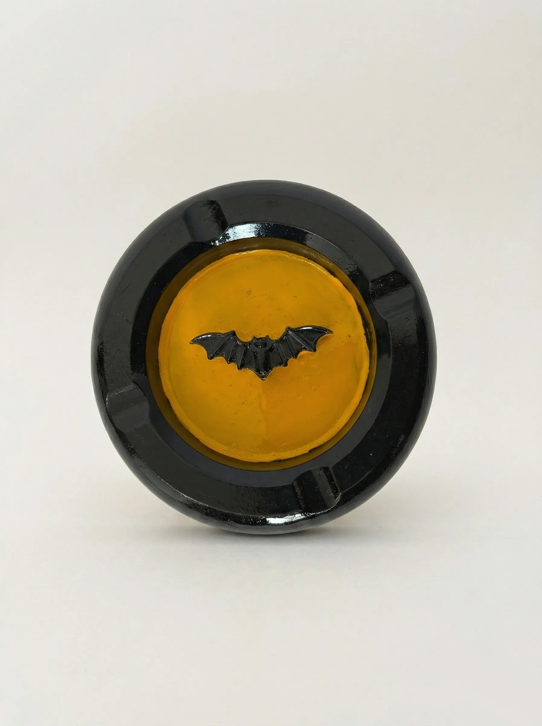 Black concrete bat-man ashtray with a yellow center and bat design on a white background