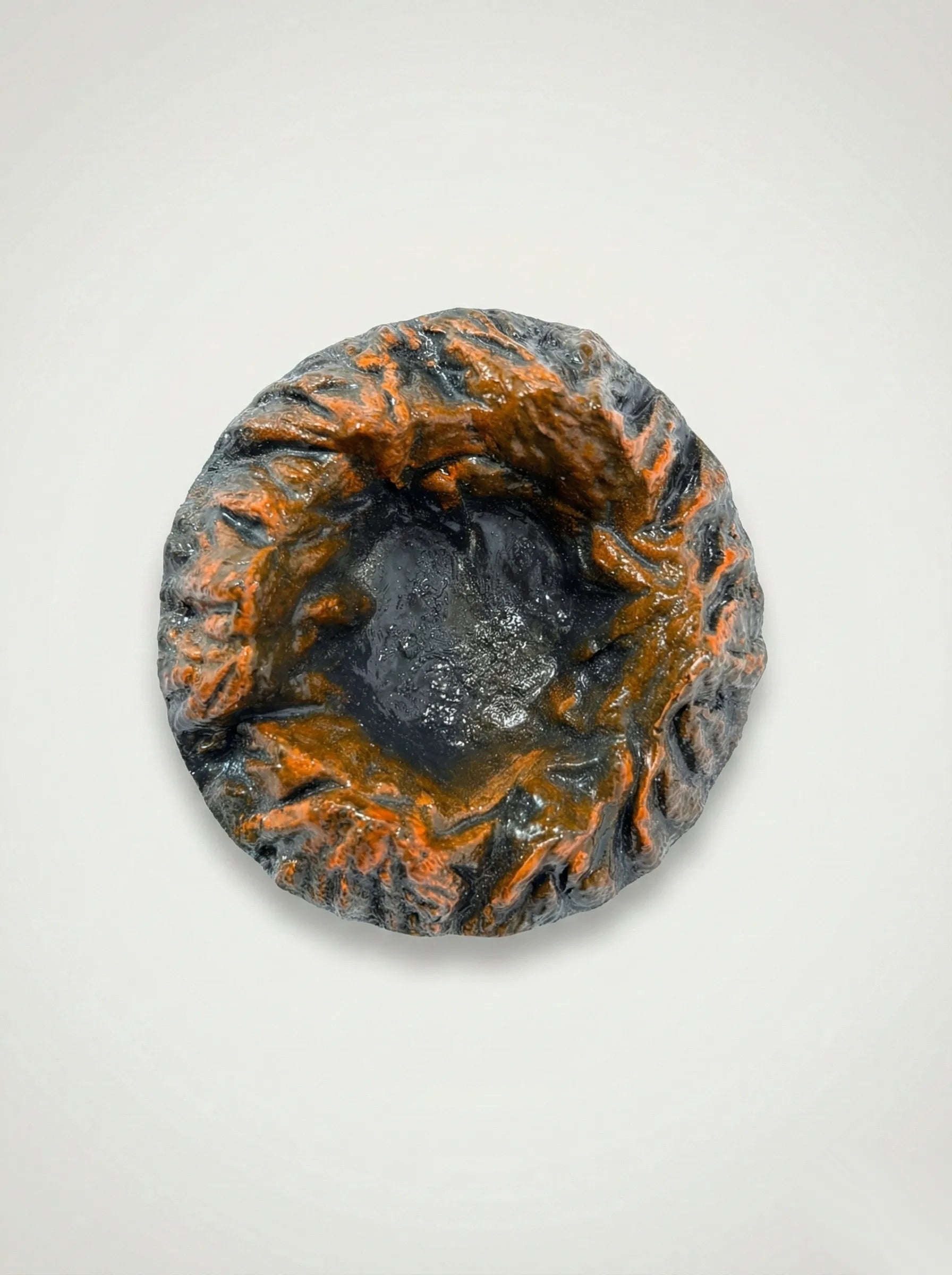Black Magma ashtray with orange and black patterns on a light gray background
