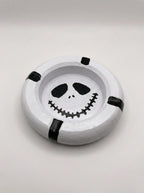 Round white ashtray with mime face design on a light gray background