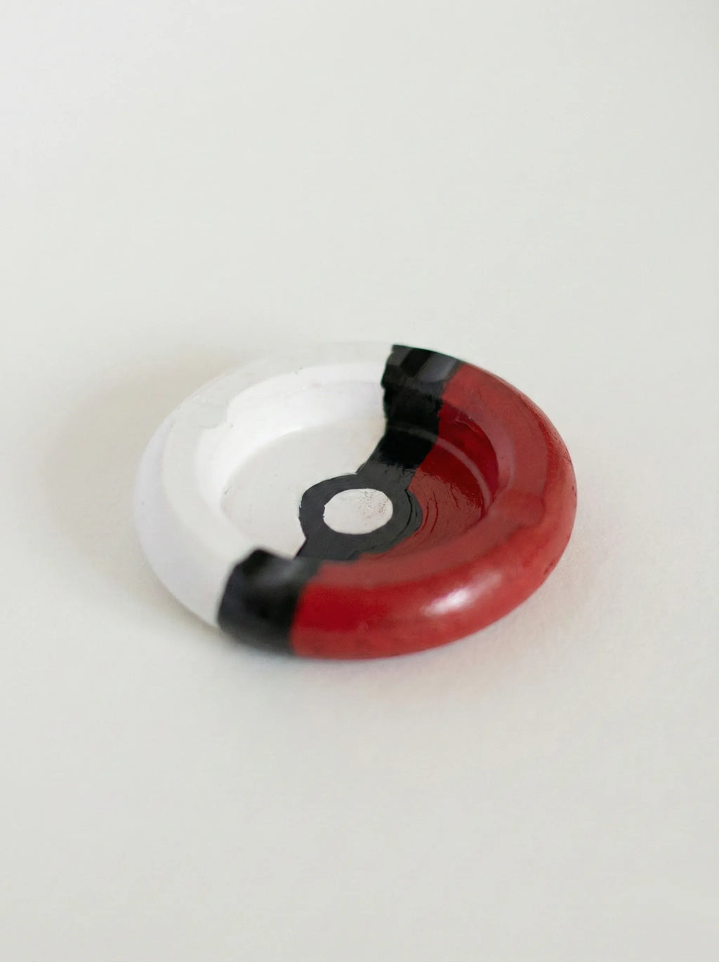 Poké Ball-like ashtray with red, white, and black design on a light gray background