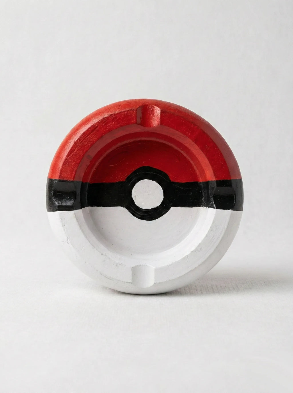 Circular pokeball ashtray with red, black, and white design on a light gray background