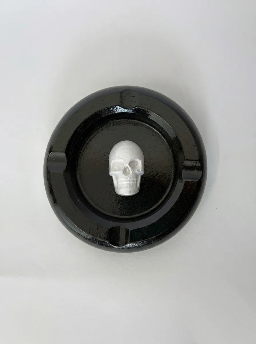 Black ashtray with a white skull design on a white background