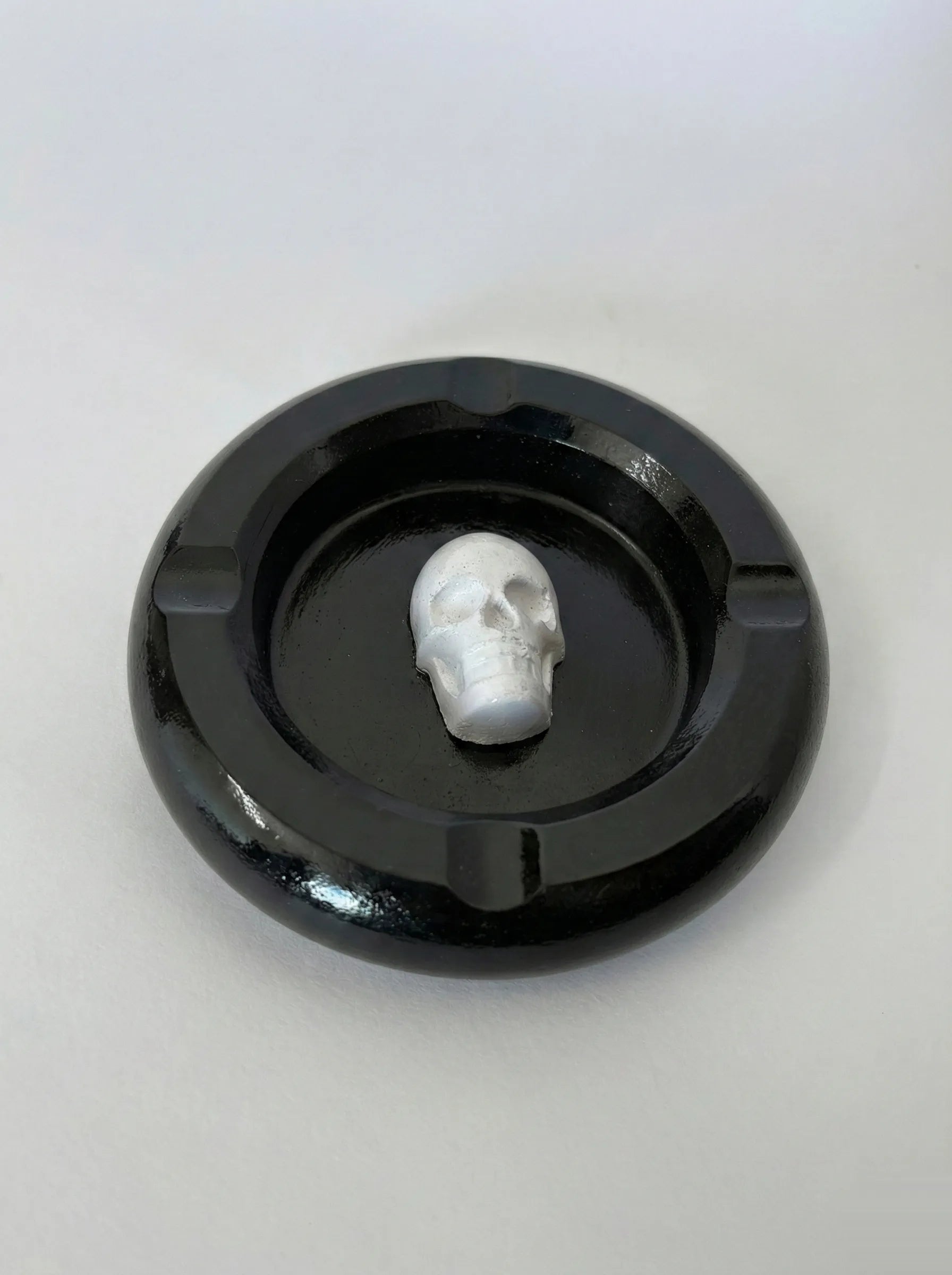 Black concrete ashtray with a white skull on a light gray background