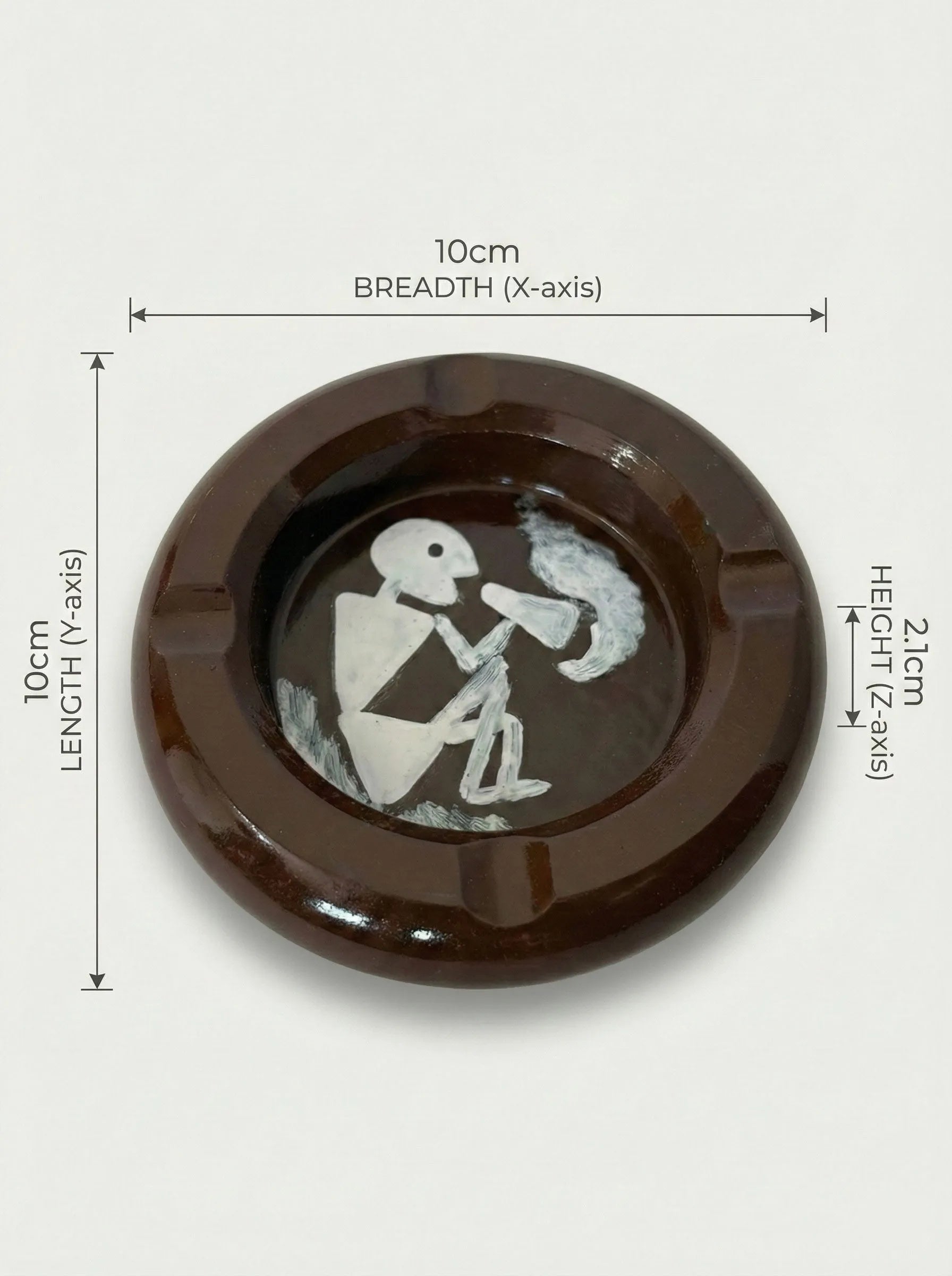 Brown round ashtray with a white design of a warli art smoking a cigarette, shown with measurements on a white background