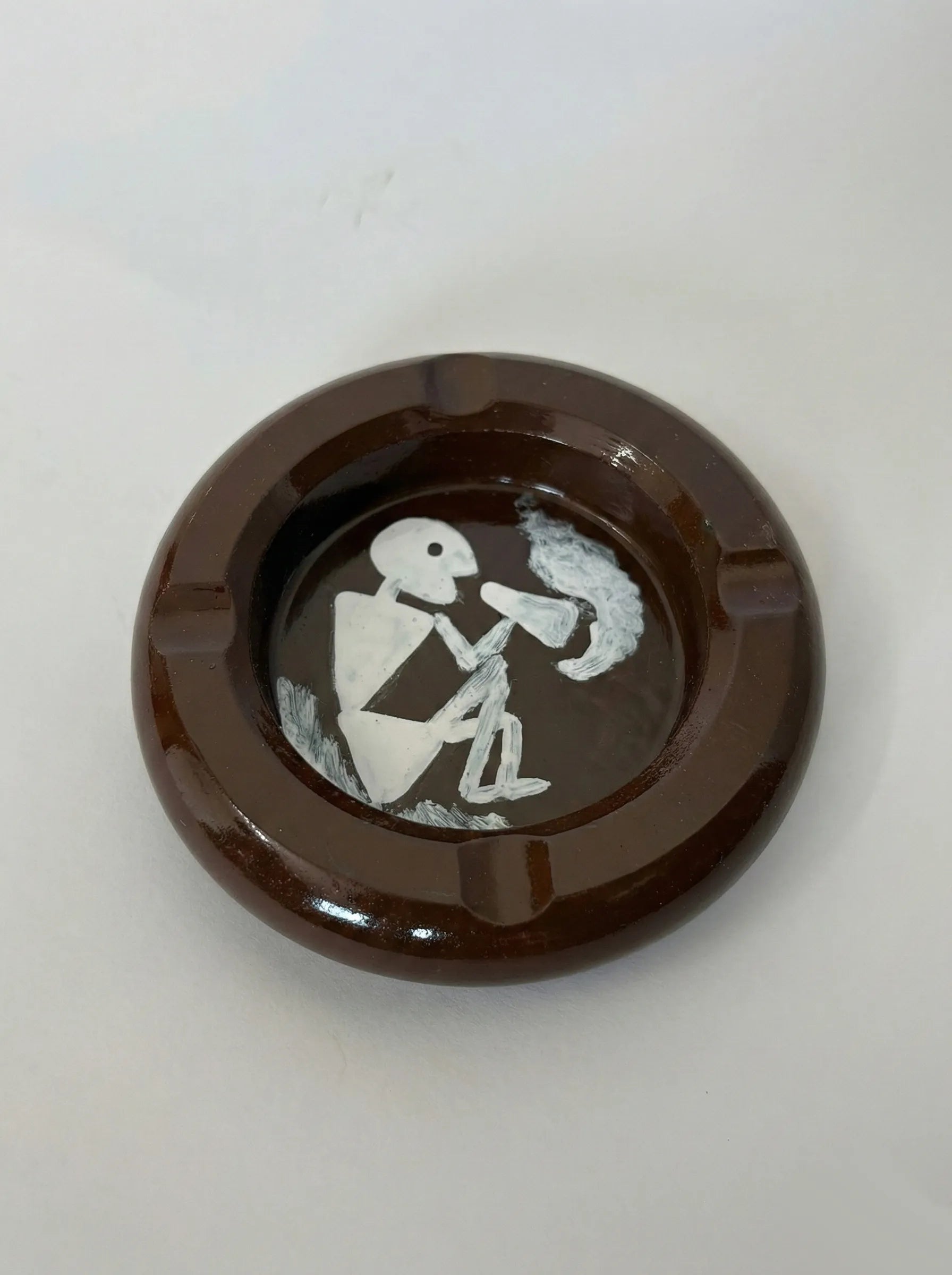 Brown ashtray with a white Warli design on a white background