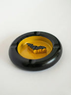 Black bat-man ashtray with a yellow center and bat design on a white background