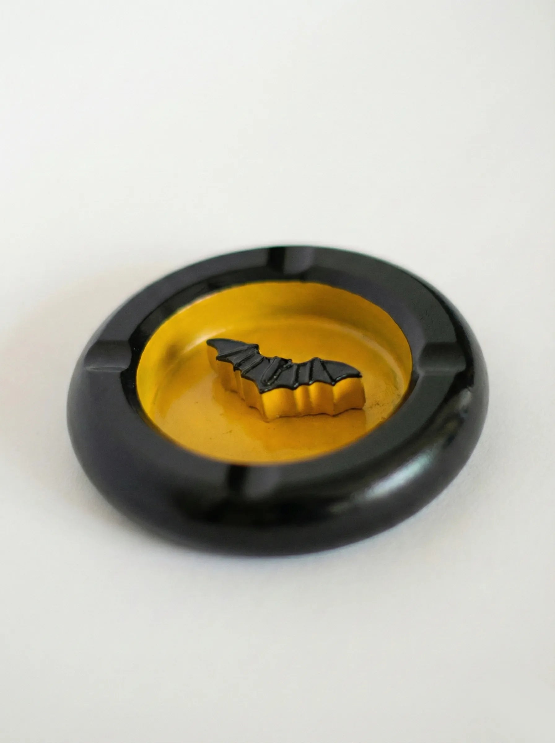 Black bat-man ashtray with a yellow center and bat design on a white background
