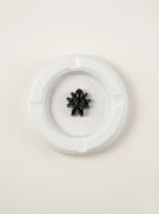 Black fancy spider on a white concrete ashtray on a off white background
