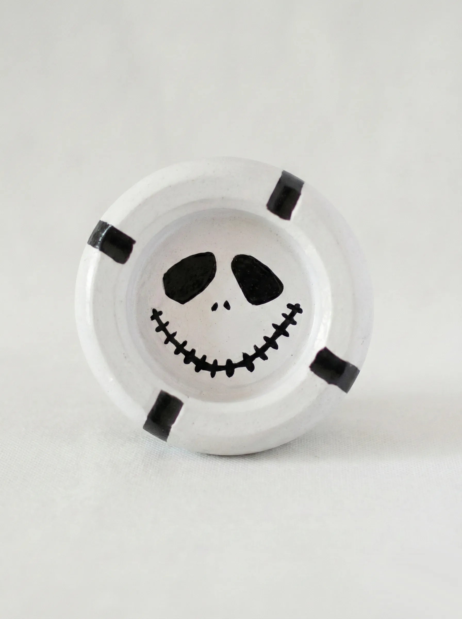Round white ashtray with a mime face design on a white background